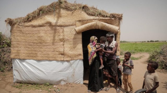 family standing infront of a hut