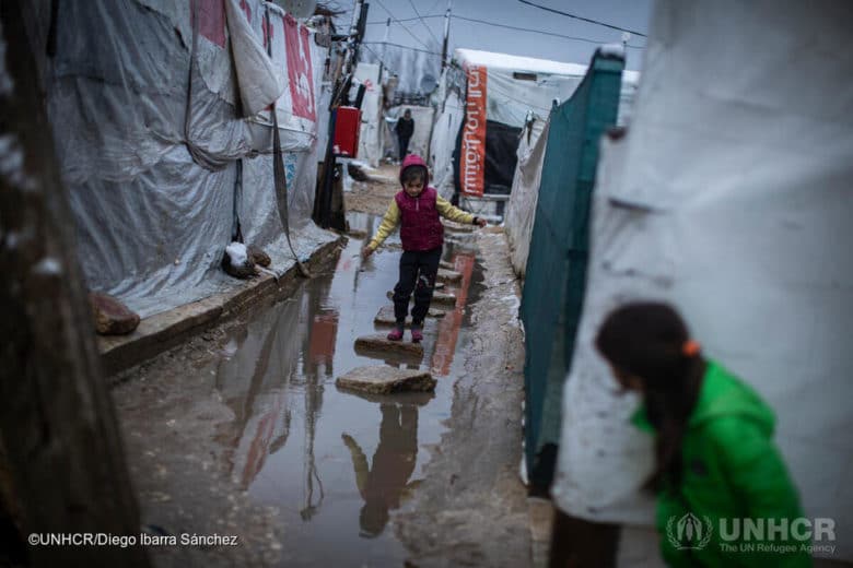 A young Syrian refugee walks through a flooded informal settlement camp after a heavy storm in Beqaa Valley.