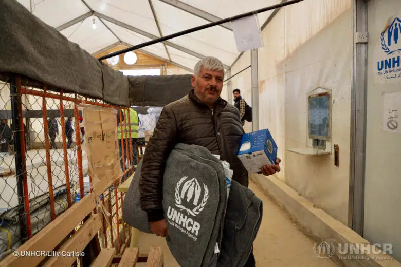 A Syrian refugee picks up blankets and a solar lamp during the distribution of winter supplies in Zaatari camp, Jordan