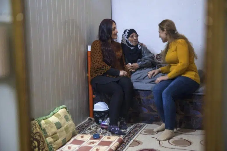 La réfugiée syrienne Falak Selo (à droite) parle à sa mère et à sa soeur dans le camp d’Akre, au nord de l’Iraq, où elle apporte un soutien en matière de santé mentale à d’autres réfugiés (26 janvier 2020)