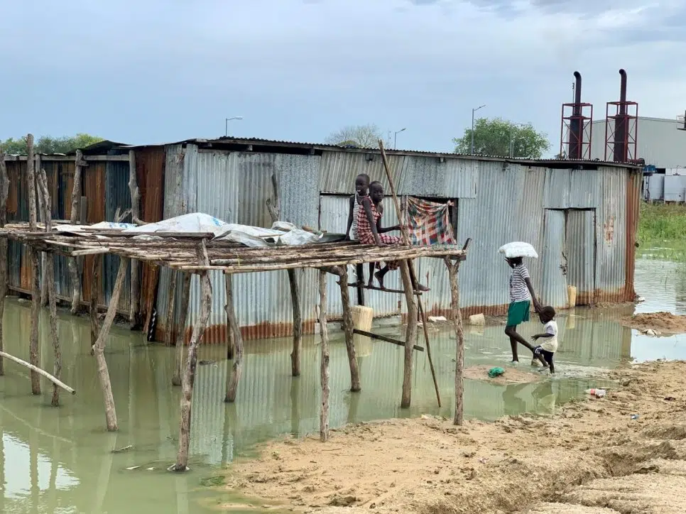 Refugees sitting and standing outside flooded home