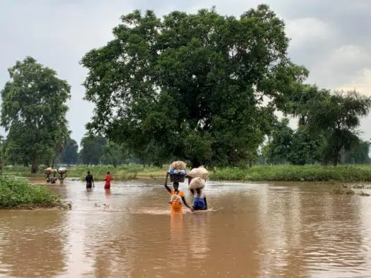 Family carrying items above their heads in high flood waters