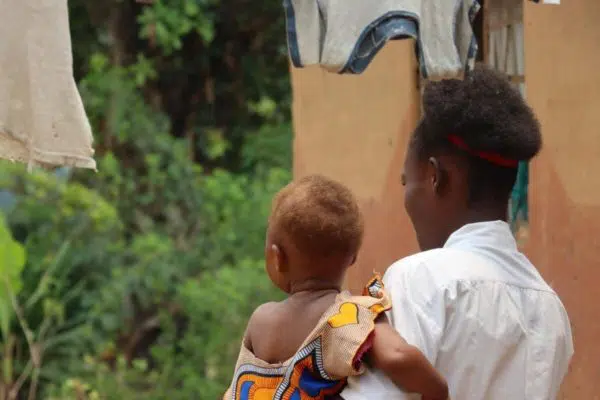 Femmes tenant un enfant, face à la caméra.