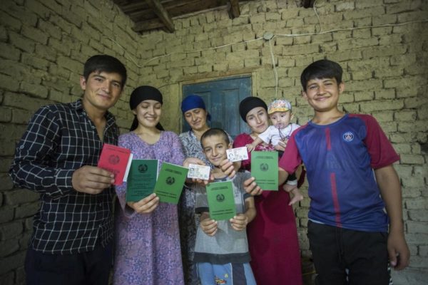 Group of seven adults and children holiding identity documents facing the camera