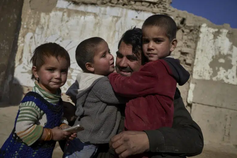 Father holding his 3 kids in Afghanistan.