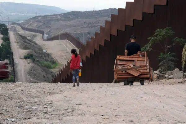 Person walking along a border fence.