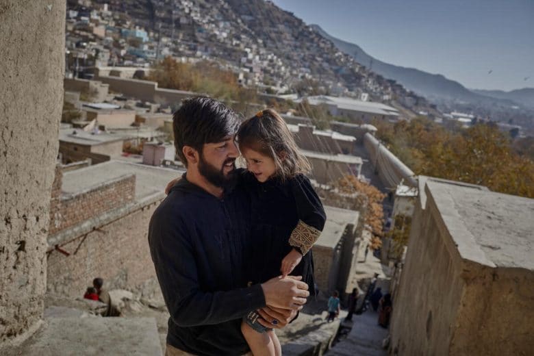 Safa’s husband, Abdul Sattar, holds their 4-year-old daughter outside their room in Kabul