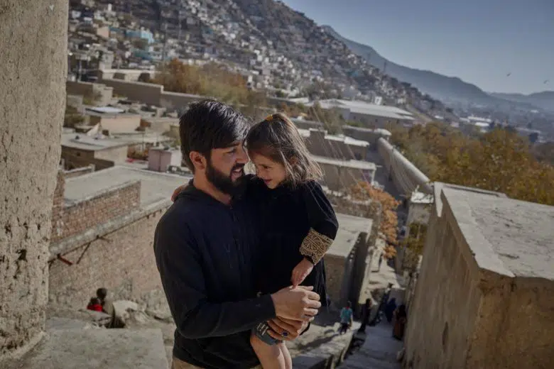 Safa’s husband, Abdul Sattar, holds their 4-year-old daughter outside their room in Kabul