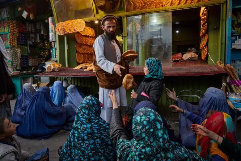Women and children, some of them displaced to Kabul by the conflict, beg for bread outside a bakery