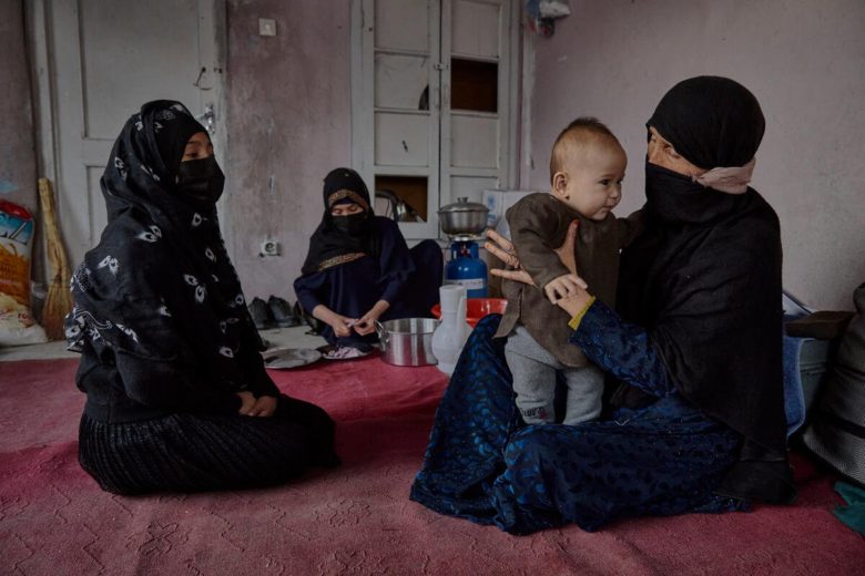 Zarina holds her six-month-old baby, Asad, in the room she has been renting in Kabul for herself and her three children, since her husband was killed in July