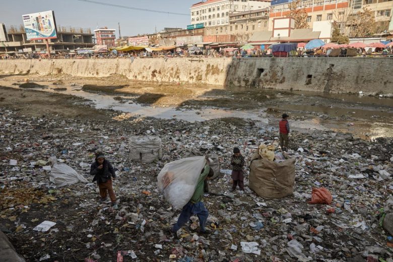 Children collect plastic from the banks of the Kabul River