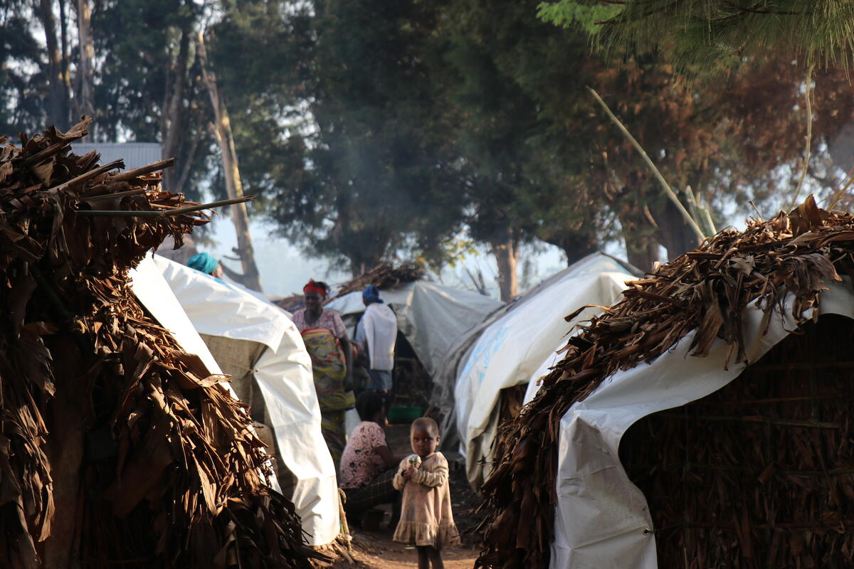 A young girl stands beside emergency shelters for recently displaced people at a site in Masisi, North Kivu