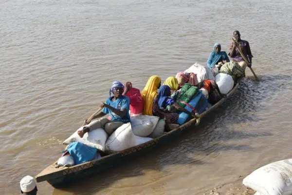 Group of people in a row boat in a river with supplies.