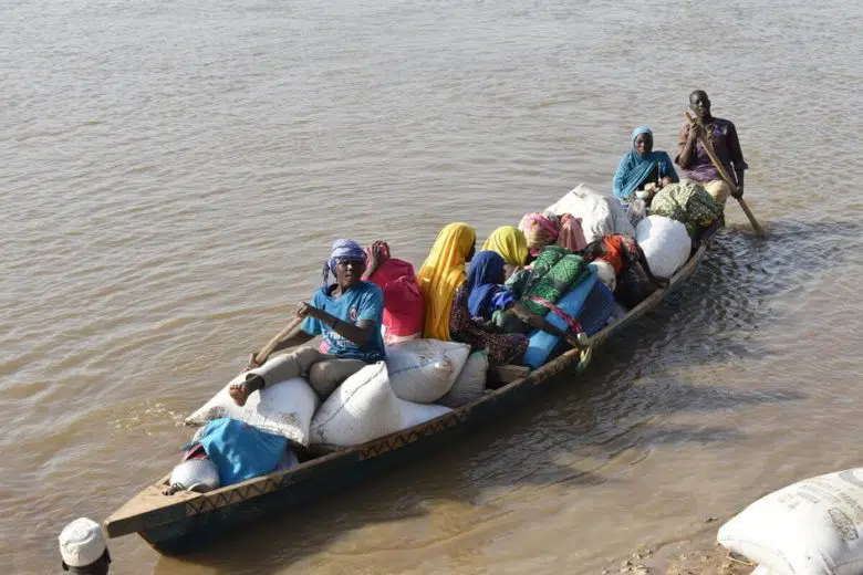 Group of people in a row boat in a river with supplies.