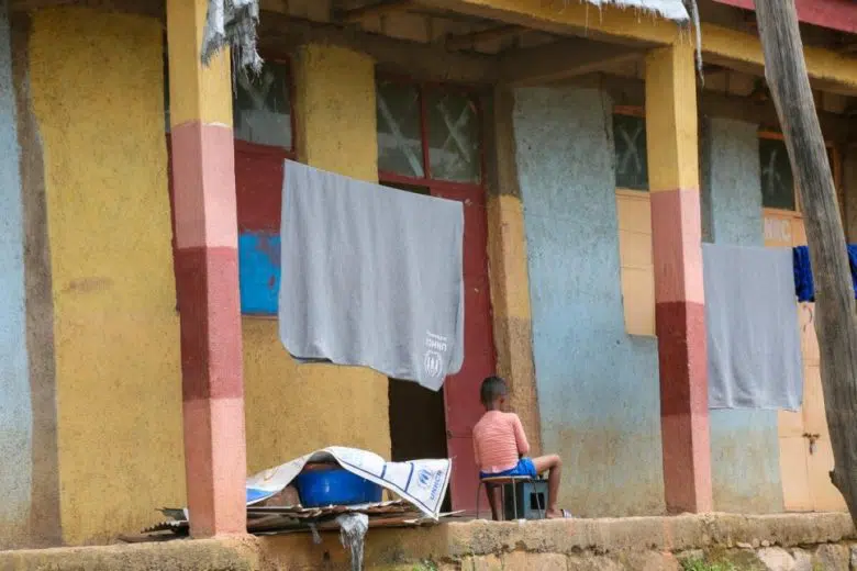 Child sitting on a chair facing away from the camera under a clothesline.