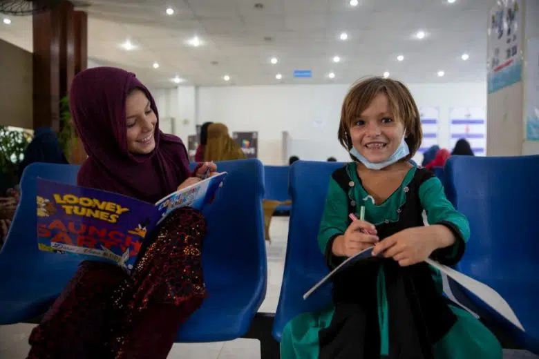 Two people smiling while reading books. 