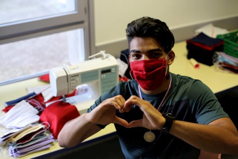 Man wearing mask and making heart shape with hands.