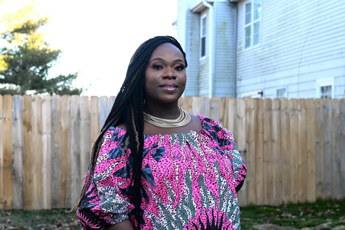 Lourena Gboeah-Flomo stands in front of a brown wooden fence