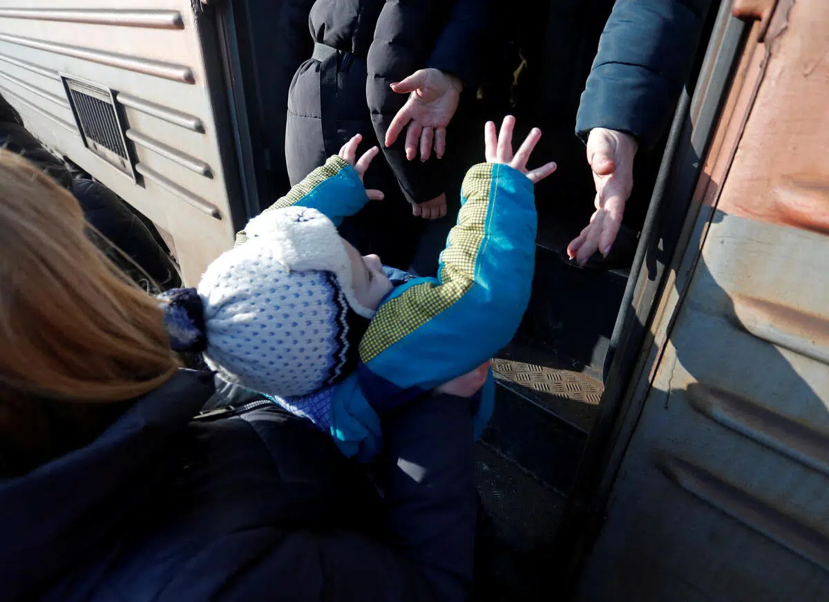 Child reaching out, being handed into a bus
