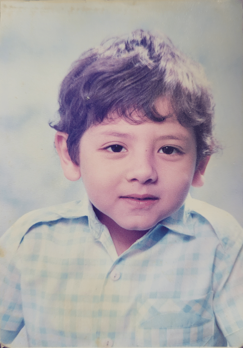 Yearbook photo of child in blue button-up shirt sitting in front of white-blue marbled backdrop.
