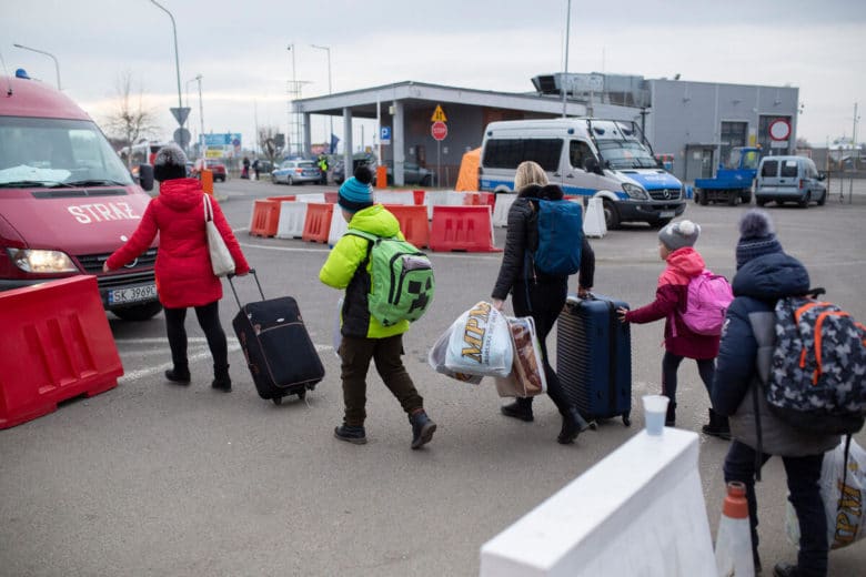 Des réfugiés ukrainiens entrent en Pologne au poste frontière de Medyka avec de nombreux sacs.
