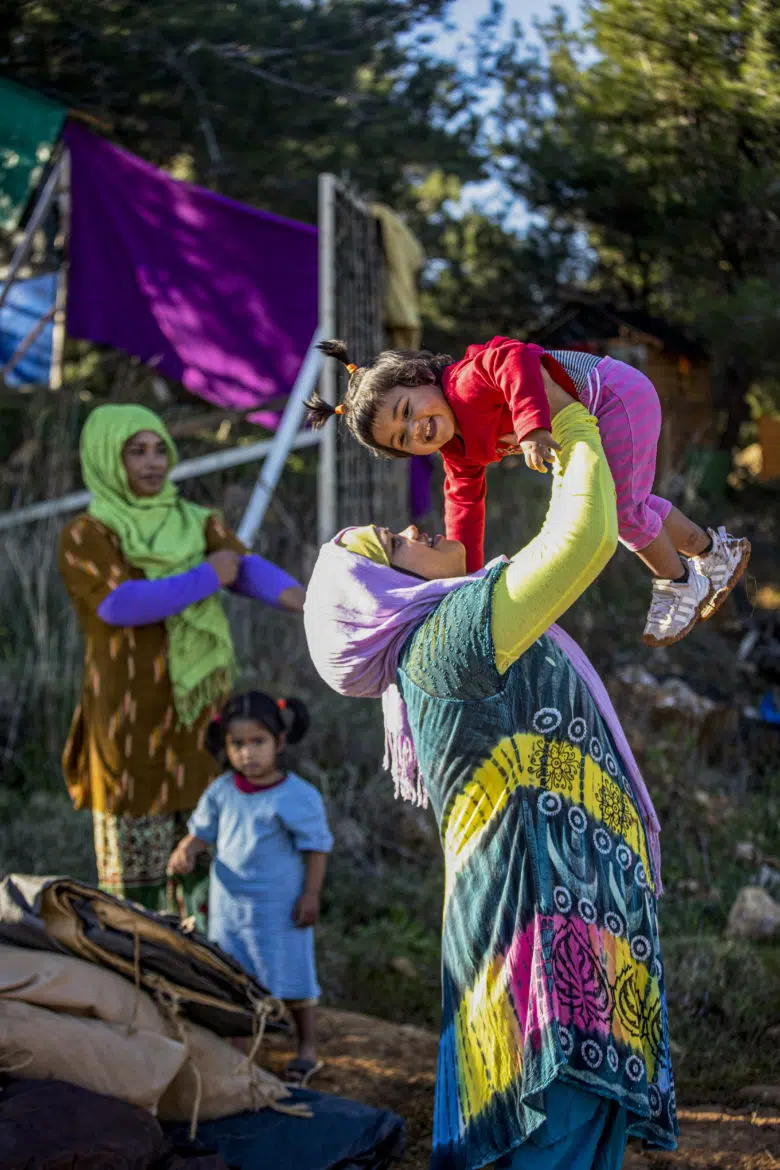 Woman in brightly coloured dress plays with happy baby