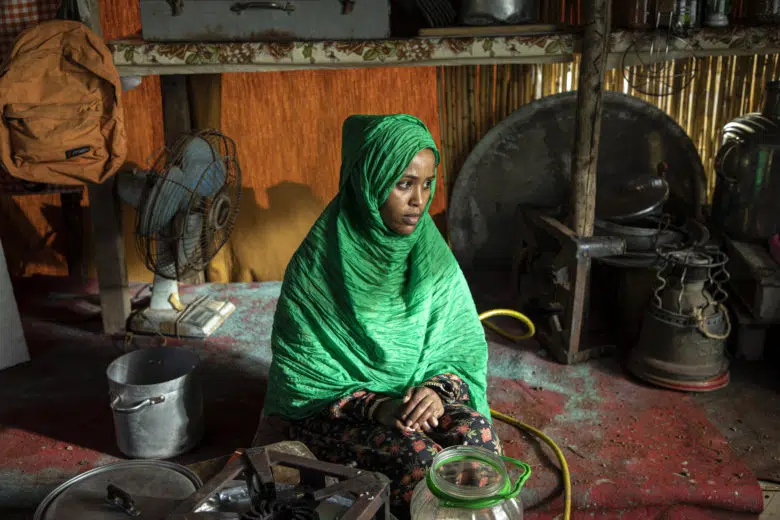 Woman sitting on the floor of a tent wearing a green hijab