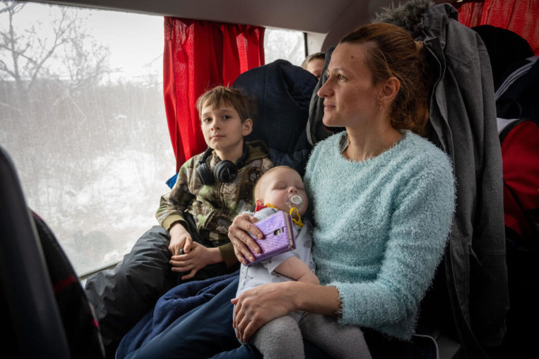 Mother and 2 children riding on a bus.