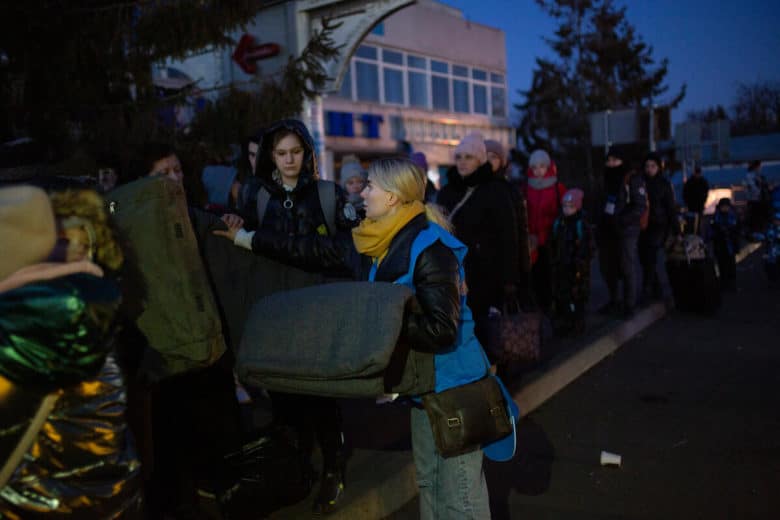UNHCR staff member handing out blankets to a line-up of Ukrainians.
