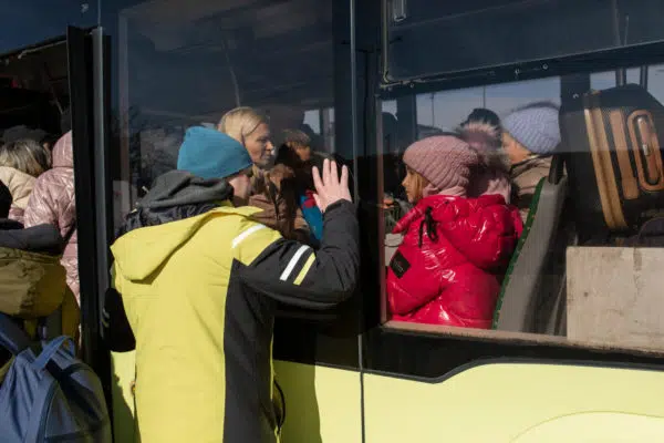 A man is waving to his family as they flee the war in Ukraine by bus.
