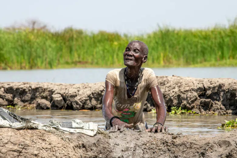 Une femme âgée construit un mur de boue fait à la main pour protéger sa famille des inondations.