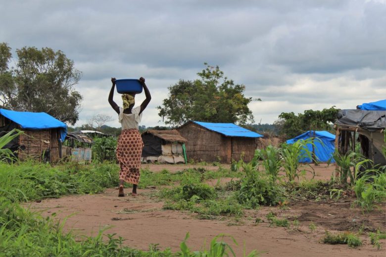 Une femme porte un seau en traversant un camp de réfugiés.