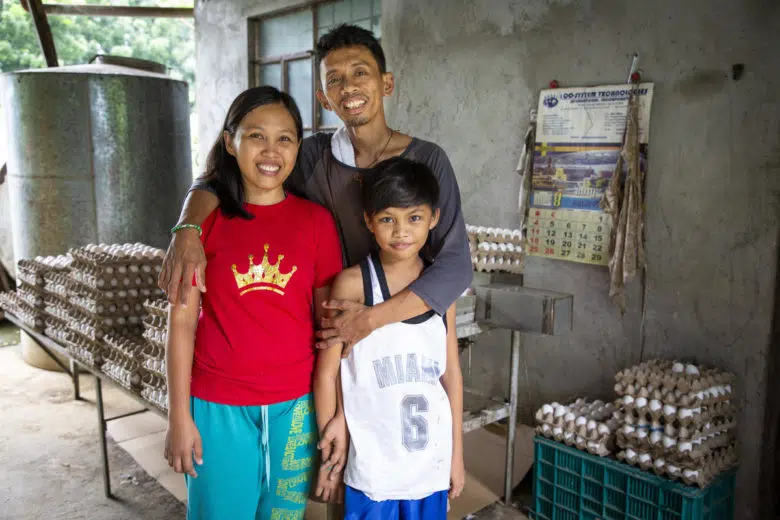 Famille de trois personnes souriant à la caméra.