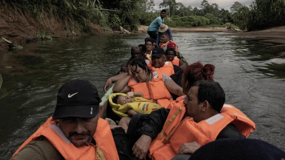 Migrants cross a river in a large canoe.