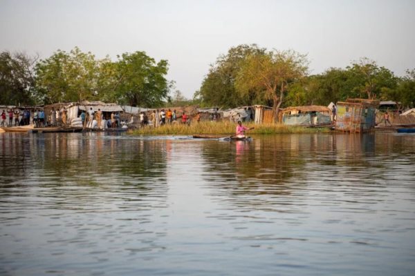 Woman paddling on a raft in South Sudan from a distance in a remote village.