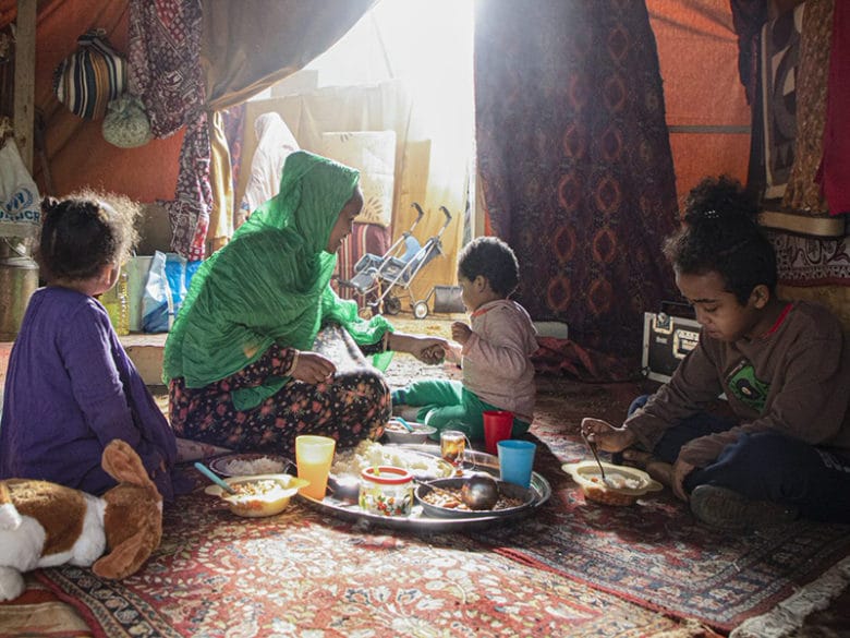 Family gathered in tent to eat a meal
