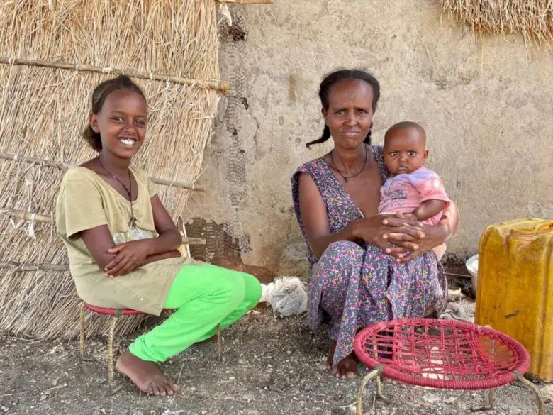 Famille de réfugiés réunis souriant à la caméra.