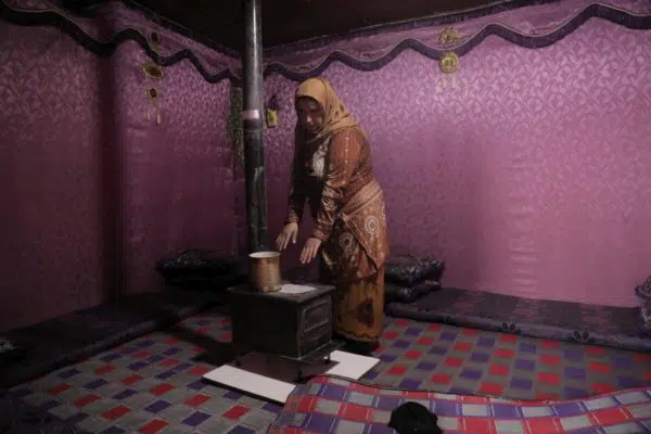 Une femme se tient devant un poêle à bois dans sa maison.