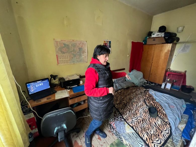 Woman standing over a bed she's offered to IDPs in Ukraine. 