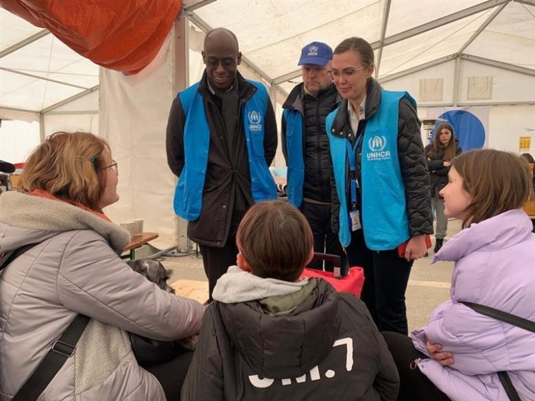 Ukrainian refugees interact with UNHCR staff at an intake center.