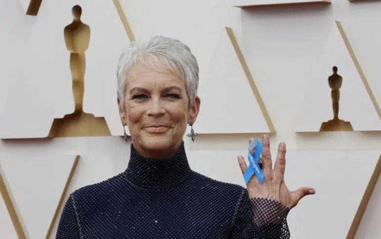 Woman holding a ribbon reading “With Refugees” at the Oscars.