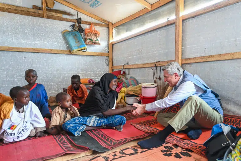 Haut-commissaire des Nations Unies assis et parlant avec une famille de réfugiés.