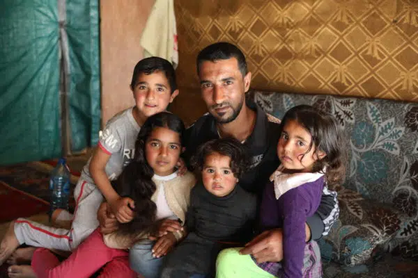 Syrian father sitting with his four young children in his arms