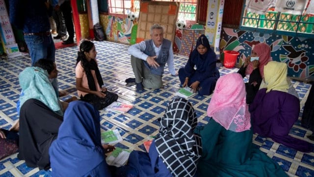 High Commissioner Grandi sitting in a circle speaking to a group of young women
