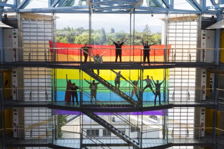 People celebrating in front of a pride flag.
