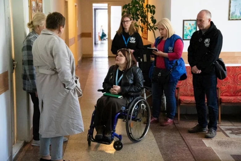 Woman in wheelchair talking to staff. 