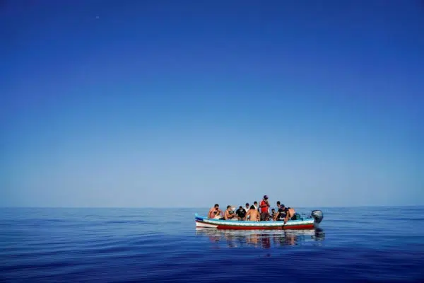 Small boat filled with people in the middle of the ocean