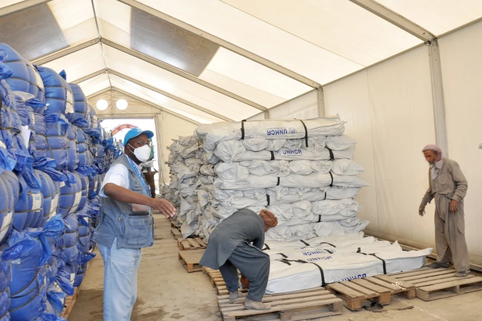 Three people inside white tent with blue and white 