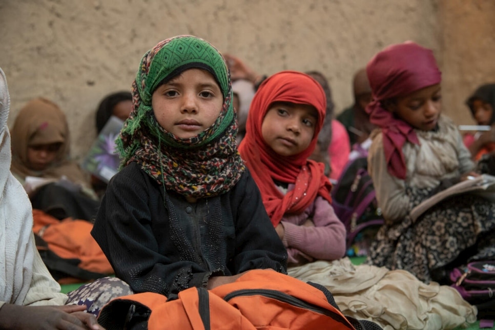 group of young children with one looking at the camera wearing a green knitted hijab