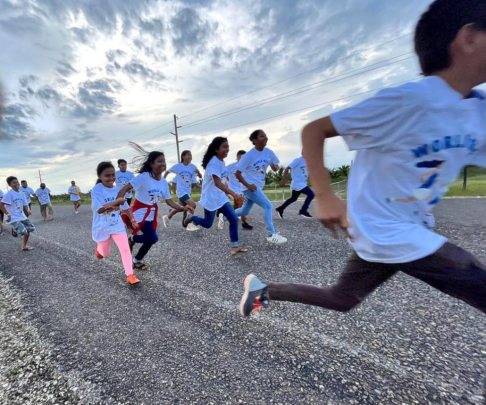 group of people running on pavement, all wearing white t-shirts